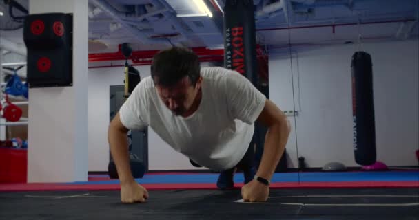 Bokser wykonuje wyciskanie na ławce, ćwiczenia push-up z podłogi, na siłowni. — Wideo stockowe