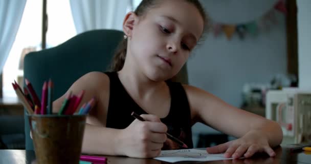 儿童绘画、重点突出的儿童初等教育概念。7-8岁的小女生或可爱的小学生在家里休息一下，坐在家里用彩色铅笔在纸上画画. — 图库视频影像