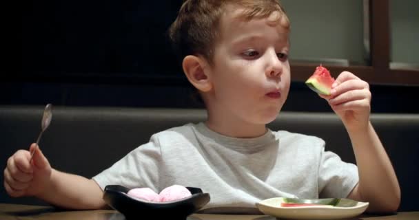 Lindo niño preescolar saludable comiendo helado con sandía, fruta de plátano sentado en un café para niños. Feliz niño comiendo comida orgánica y vegana saludable en el restaurante. Infancia, salud — Vídeos de Stock