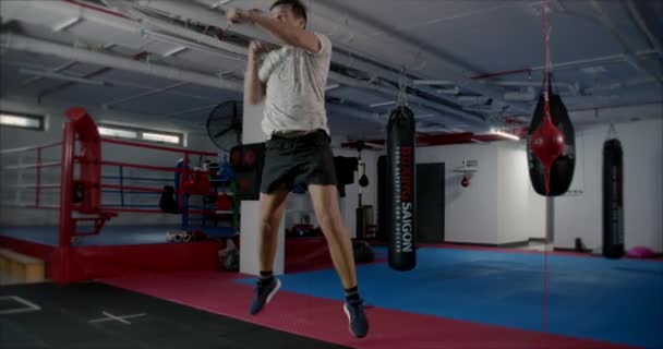 Sportowiec Boxer wykonuje skoków w sali bokserskiej, popycha się i sprawia, ciosy do przodu, ćwiczenia sportowe w siłowni. — Wideo stockowe