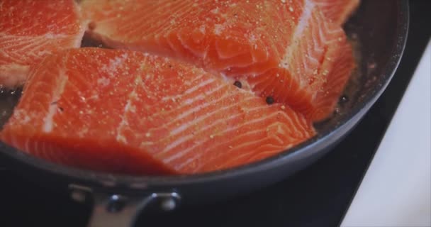 Pedaços de deliciosos peixes cozinhados na cozinha. O filete do peixe vermelho frita-se em uma panela. Frutos do mar. Preparação de Salomão. Um pedaço de peixe com especiarias. Comida dietética. Almoço quente. Macro — Vídeo de Stock