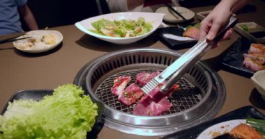 Şef tong 'u kullanıyor ve eti ızgaraya çeviriyor. Ateş yanıyor, yağlı biftek yavaş çekimde pişiyor. Izgara, lezzetli biftek yavaş çekimde yakın çekim..