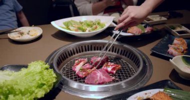 Izgara, lezzetli biftek yavaş çekimde yakın çekim. Şef tong 'u kullanıyor ve eti ızgaraya çeviriyor. Ateş yanıyor, yağlı biftek yavaş çekimde pişiyor..