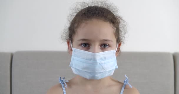 Portret słodkie małe dziecko lub dziewczynka w ochronnej masce medycznej, ze smutną rozczarowaną twarzą. Dziewczyna w masce medycznej. Pandemia, covid - 19. — Wideo stockowe