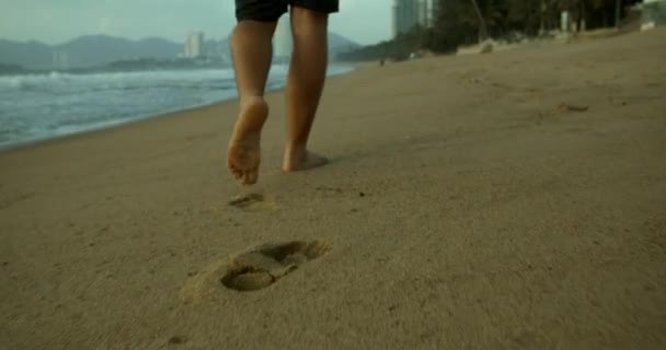 Ung kaukasin man tränar med utomhus kör med en vacker havsbakgrund. Jogga på sanden på stranden vid solnedgången mot bakgrund av det vackra havet, stora vackra vågor. — Stockvideo