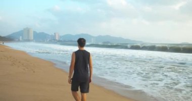 Sahilde kumsalda yürüyen bir adam açık havada güzel denizin arka planında.