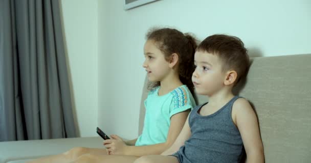 Дитячий брат і сестра дивляться телевізор. Портрет милих маленьких дітей під час перегляду телевізора на ноутбуці. Бой і дівчинка Дивитися мультфільм на ноутбуці на вітальні. Концепція відеоігри, розваги, емоції, сім'я — стокове відео