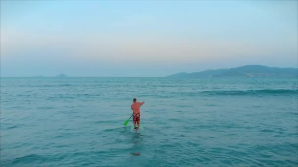 Surfer vliegt op de kam van een golf, een surfer bestuurt de roeispaan, staande op een surfplank. Surfer wacht op zijn golf.. — Stockvideo