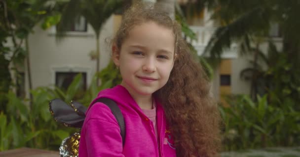 Cute kid child with pretty face on street. Concept of a happy childhood. Funny portrait little girl smiling child looking at camera are walking on street, — Stock Video