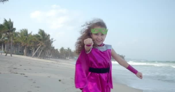 Anak bermain superhero membuat gerakan penerbangan, terbang ke depan dengan tangannya terangkat ke depan. Bayi perempuan bermain superhero. Lucu anak dalam jas hujan merah dan topeng bermain kekuatan super pahlawan. — Stok Video