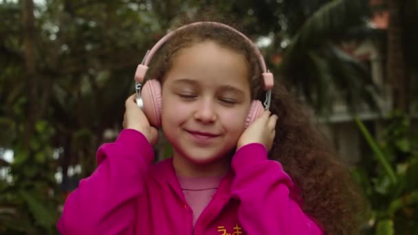 Nagranie z nieostrym portretem Cute Little Girl With Headphones Listening to Music. Slow Motion Of Child On Relaxing on With Eyes Closed Wearing Headphones. Kid słuchanie muzyki w domu. — Wideo stockowe
