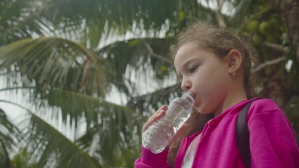 Nettes kleines Mädchen trinkt ein Glas Wasser in einem Café. Zeitlupe Kind trinkt Wasser. Nahaufnahme. Das Kind trinkt eine Tasse Wasser. — Stockvideo