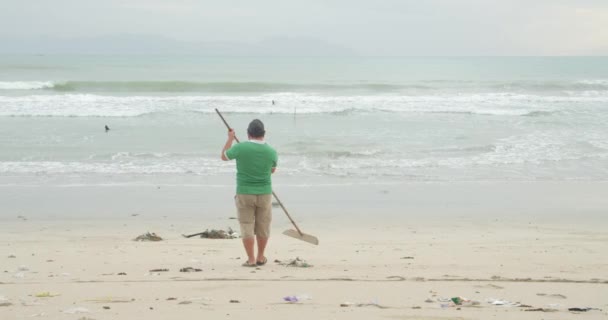 Environmental awareness concept copy space. Volunteer man cleaning up white beach. The volunteer raises and throws a plastic garbage into the bag. Volunteering and recycling concept. — Stock Video