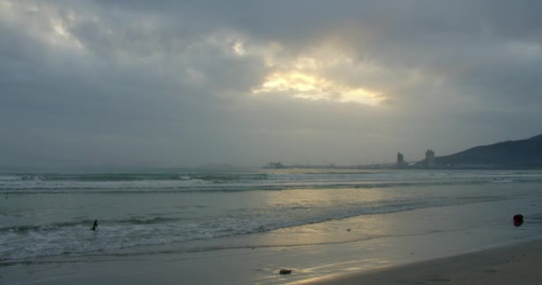 Eine große Sonne erscheint hinter den Wolken, und große Berge berühren den Horizont und die Küste. Asiatischer Strand Hintergrund. Die Spur der Sonne auf den Wellen im Sand. — Stockvideo