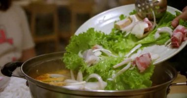 Müşteri masasındaki restoranda şef çorba hazırlar, malzemeleri, sebzeleri, eti, deniz ürünlerini güvecin içine döker, Vietnam ulusal lao çorbasını yakın plan yapar..