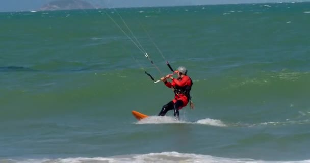 Athlete showing sport trick jumping with kite and board in air. Extreme water sport and summer vacations concept. Acrobatic jump of professional kite surfer on the sea wave. Slow motion — Stock Video
