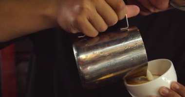 Barista özel kahve dükkanında latte yapıyor. Profesyonel bir adam espresso ile süt dolduruyor.