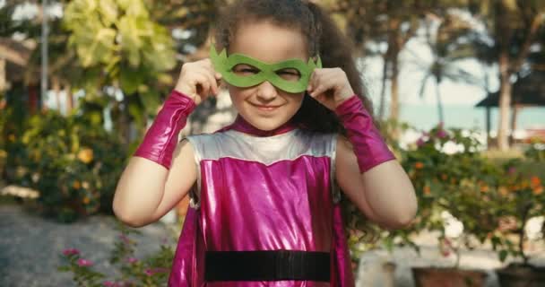 超级英雄服装中漂亮的女婴，孩子扮演超级英雄，穿着粉色斗篷和英雄面具的孩子。超级英雄和权力的概念。特写特写. — 图库视频影像