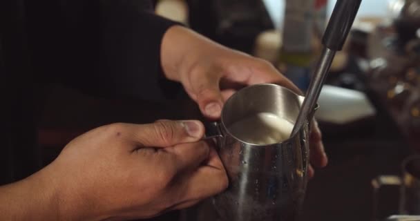Professionele barista. Het maken van vers gemalen koffie, Barista het maken van Latte Art giet melk in een mok tijdens het maken, waardoor de koffie nog meer wenselijk. — Stockvideo