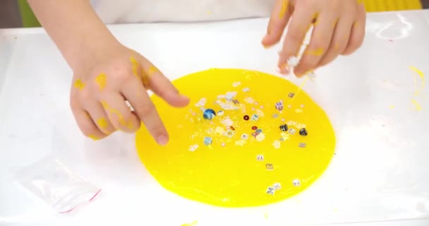 Children sculpt and play with glitter textured slime, stretching the sticky substance for fun. Close up and top view of kids hand holding pink and yellow shiny goo while squeezing it. — Stock Video
