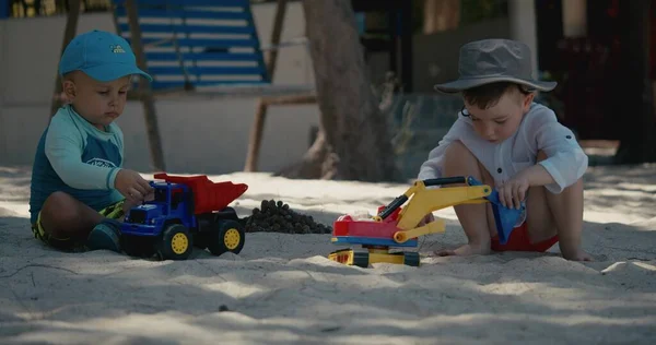 Çocuklar plajdaki kumda plastik bir arabayla oynuyorlar. Sahilde kumla oynayan çocukların elleri, plastik oyuncaklar..