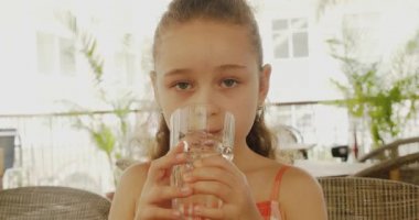 Bir kafede bir bardak su içen tatlı bir erkek bebek. Yavaş çekim su içen küçük çocuk. Yakın plan. Çocuk bir bardak su içiyor..