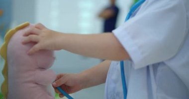 Beyaz üniforma giyen sevimli anaokulu çocuğu, evcil hayvan solunumunu, papağanları ve oyuncak hastaları dinliyor, hastane oyunu oynayan doktor, veteriner, doktor, evsizleri tedavi eden çocuk.