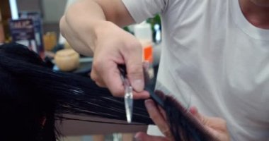 Erkek kuaför saçını tarar. Güzellik salonunda esmer bir kadının berber dükkanında, berber dükkanında saç kesimi vardır. Bir erkek berber dükkanında esmer bir kadın için saç stili yapar. 4K ağır çekim.