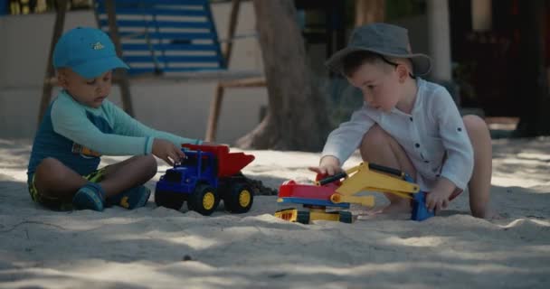 Los niños juegan con un coche de plástico en la arena de la playa. primer plano de los niños manos jugando con arena en la playa, juguetes de plástico. — Vídeo de stock