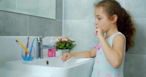 Retrato feliz lindo niño pequeño cepillándose los dientes en el baño y sonriendo. Rutina diaria de salud infantil. Niño caucásico con diente blanco mirando el espejo aislado en casa. Estilo de vida. — Vídeo de stock