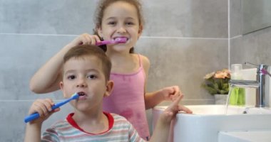 Portre mutlu genç çocuklar banyoda dişlerini fırçalıyorlar ve gülümsüyorlar. Çocuklar günlük sağlık hizmeti rutini. Beyaz çocuklar evlerinde aynaya bakıyorlar. Yaşam biçimi.