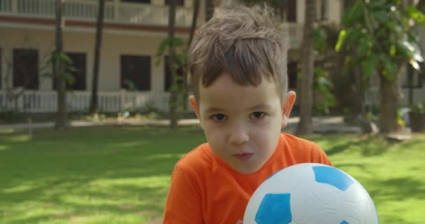 เด็กน่ารักเล่นบอลกีฬากลางแจ้งไลฟ์สไตล์ในสวนสาธารณะเพื่อสุขภาพ เด็กเล่นฟุตบอลในวันฤดูร้อน . — วีดีโอสต็อก