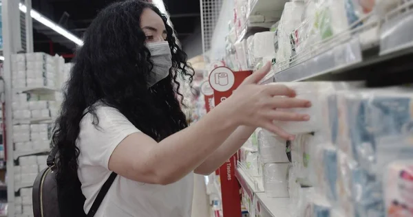 Coronavirüs salgınından maske takan genç bir kadın süpermarketten tuvalet kağıdı alıyor. Corontin, izolasyon.