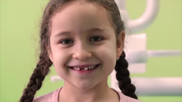 Close Up Little Girl With Curly Hair and Two Pigtails in the Dental Chair Smiles and Looks at the Camera to Show Where She lost a Few Teeth. — Stock Video