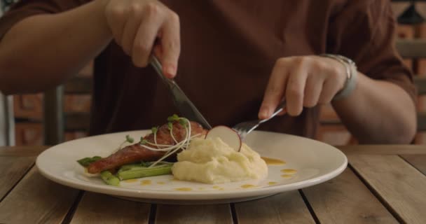 Ung kvinna äter läcker lasso vattnas med passionsfrukt sås, flicka äter potatismos och örter, sparris hälsosam mat på en plats.Professionellt tillagad lax i restaurang eller middag hemma — Stockvideo