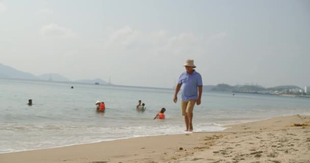 Сім'я у відпустці плаває у морі з дітьми і батьками, дорослими і дітьми, вода у відпустці. Чоловічий турист іде по піску повз туристів, які відпочивають. Азія, Нха Транг, В "єтнам, 24 квітня 2021 року. — стокове відео