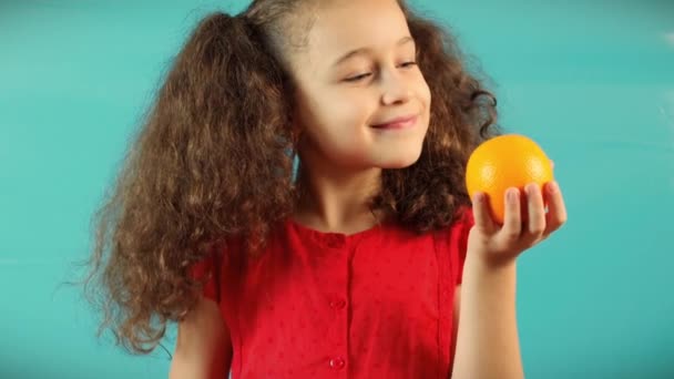 Cute Child on Turquoise Background of Holding a Green Apple and Orange and Choice Healthy Eating between Fruit and Orange.Little Kid Makes a Choice Between of Holding a Green Apple and Chocolate — Stok Video