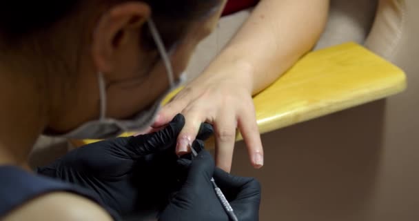 Професійний космолог проводить процедуру, готує і обробляє нігті клієнтів, видаляє кутикули перед педикюром. Дівчина-космолог робить манікюр брюнетці в перукарні . — стокове відео