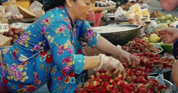 Província de Han Hoa, Vietnã, 9 de maio de 2021.Mulheres idosas vietnamitas vendem frutas tropicais frescas, morangos em um mercado de rua na cidade turística, pessoas mascaradas no mercado devido à epidemia global de Covid 19 — Vídeo de Stock