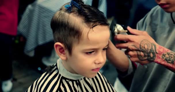 Província de Han Hoa, Vietname, 14 de Maio de 2021. Corte de cabelo de crianças em uma barbearia durante a epidemia de coronavírus. O garotinho está cortando o cabelo.Penteado das crianças. Stylist faz um penteado elegante — Vídeo de Stock