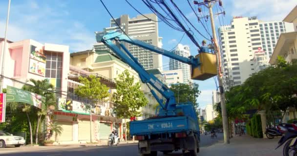 Han Hoa-provinsen, Vietnam, 12 maj 2021. En professionell elektriker arbetar i en stad på en höjd med hjälp av en kran-hiss utför arbete med högspänningsledningar binder upp samlar dem i en bunt — Stockvideo