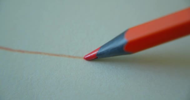 Crayon de couleur orange graphite dessine une ligne droite sur un papier de fond blanc, papier spécial pour l'artiste, prise de vue macro. Des lignes de Mans. Concept dessin, art — Video