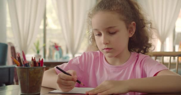 Happy Little Girl lub słodkie dziecko szkoły podstawowej 7-8 lat w domu relaks siedzi w domu i farby na papierze używać ołówków kolorów. Dziecko rysuje, skupione dzieci elementarna koncepcja edukacji. — Wideo stockowe