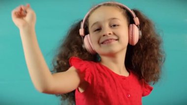 Evde turkuaz arka planda müzik dinleyen sevimli çocuk. Neşeli Kaygısız Çocukluk. Kulaklıklı Küçük Kız 'ın Müzik Dinleyen Portresi.