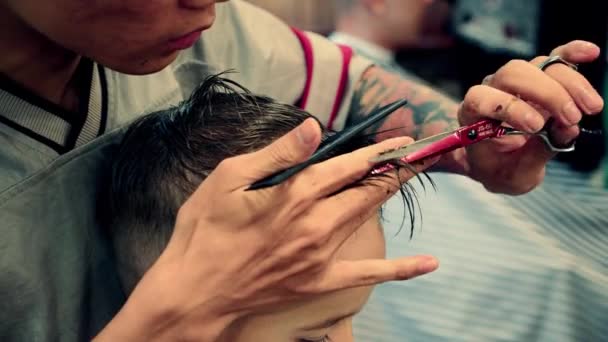 Provincia di Han Hoa, Vietnam, 14 maggio 2021. Close up Taglio di capelli per bambini in un negozio di barbiere durante l'epidemia di coronavirus.Il bambino si sta tagliando i capelli.Acconciatura per bambini. Stylist rende un'acconciatura elegante. — Video Stock