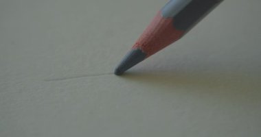 Gri grafitten yapılmış bir kalem sapı beyaz arka plan üzerine düz bir çizgi çizer, sanatçı için kağıt, makro çekim. İnsan çizgileri. Şekil konsepti, sanat