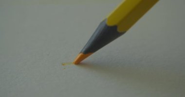 Grafit turuncu renkli kalem beyaz arka plan kağıdına düz bir çizgi çizer, sanatçı için özel bir kağıt, makro çekim. Erkek çizgileri. Konsept çizim, sanat