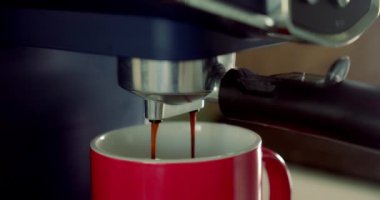 Espresso hazırlığı, ev yapımı sıcak espresso Arabika kahvesi kahve makinesinin kahve makinesinden kahve fincanına dökülüyor..