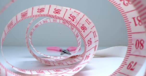 Garment factory.Super Close-up shot of a measuring tape into a roll of sewing and colored thread on the background stand.Needle, threads,measuring tape,spools of colored threads are visible in frame. — Stock Video