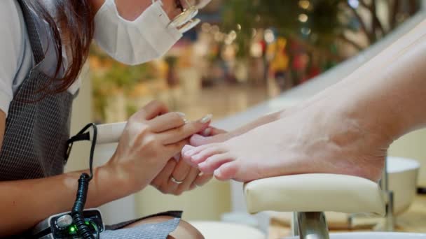 De schoonheidsspecialiste voert de procedure uit, bereidt en verwerkt de nagel van de klant met een speciale oplossing om oude vernis te verwijderen. Cosmitoloog maakt een manicure naar een brunette in een kapsalon. — Stockvideo